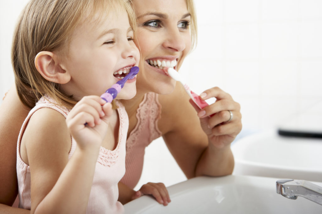 Mother and daughter brush their teeth